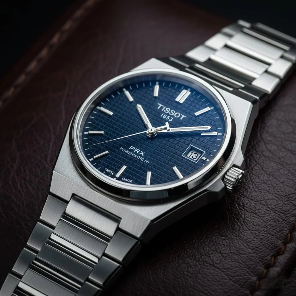 Stainless steel wristwatch with textured blue dial and date display on a leather surface