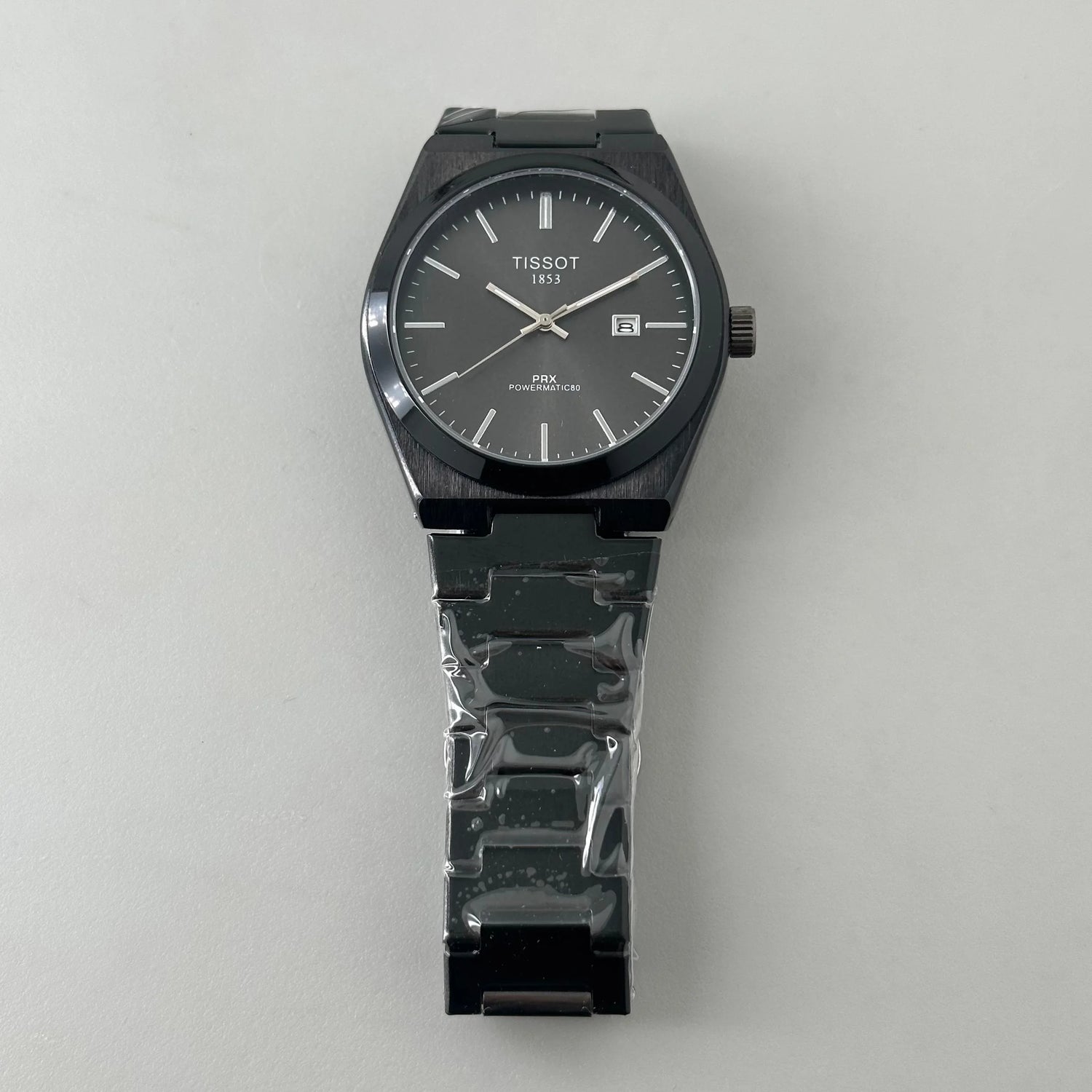 Black Tissot PRX Powermatic 80 wristwatch with stainless steel bracelet on white background