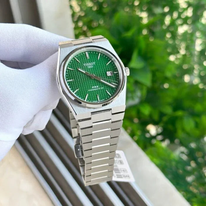 Stainless steel wristwatch with green textured dial and date display, held outdoors