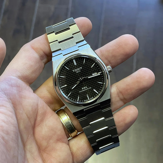 Silver stainless steel analog wristwatch with black textured dial and date display