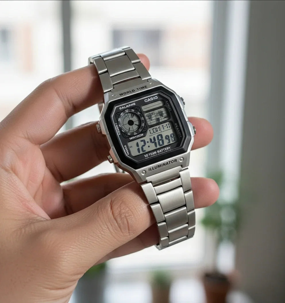 Hand holding a silver Casio digital wristwatch with metal band and rectangular display.