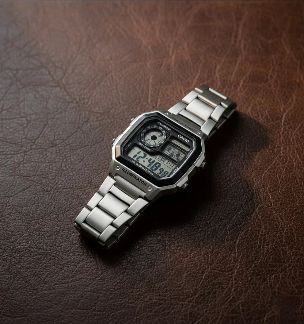 Stainless steel digital wristwatch with rectangular face on brown leather surface