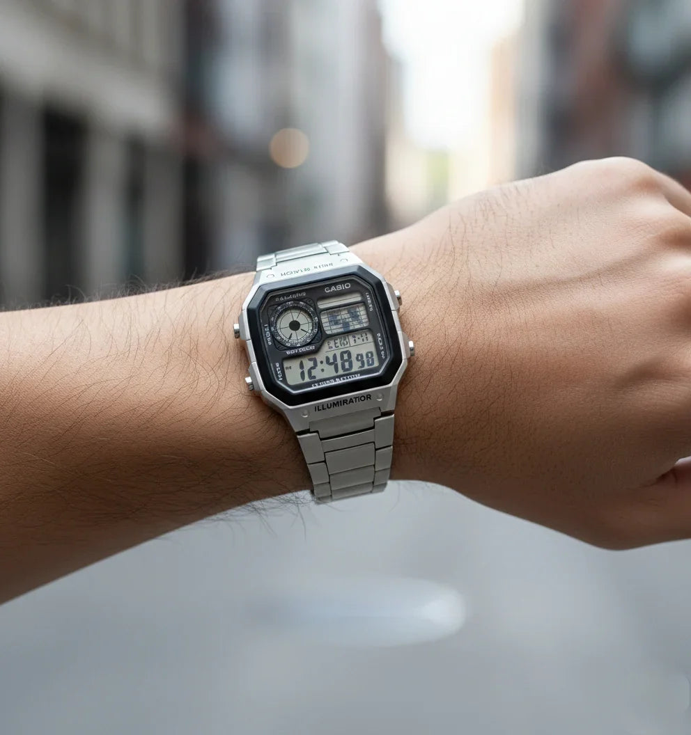 Silver digital wristwatch with rectangular face on a person's wrist outdoors