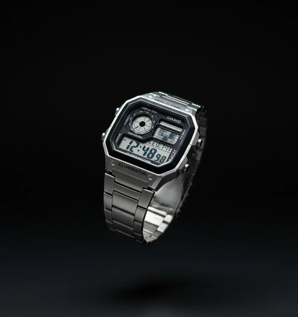 Digital silver wristwatch with metal band and illuminated display on black background